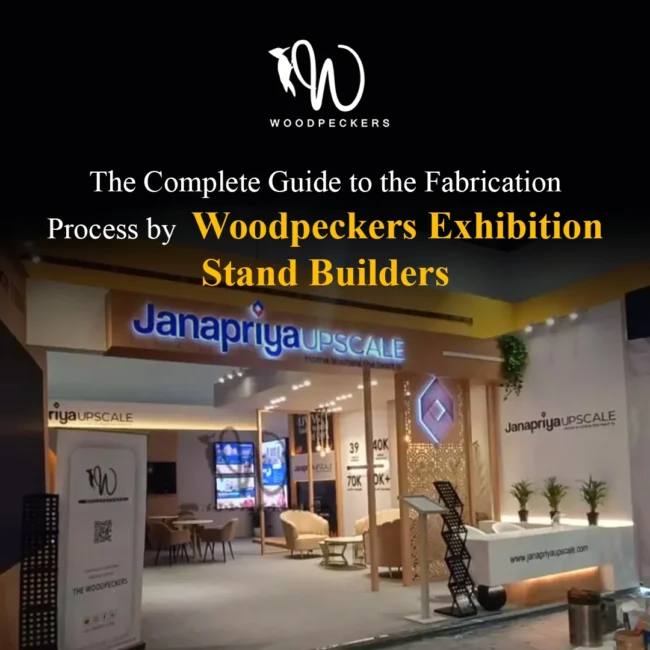 Exhibition Stand Fabrication Process by Woodpeckers – Janapriya Upscale Booth Custom fabricated exhibition stand built by Woodpeckers for Janapriya Upscale, featuring back-lit 3D acrylic branding, laser-cut jaali screens, lounge seating, and an illuminated reception counter.