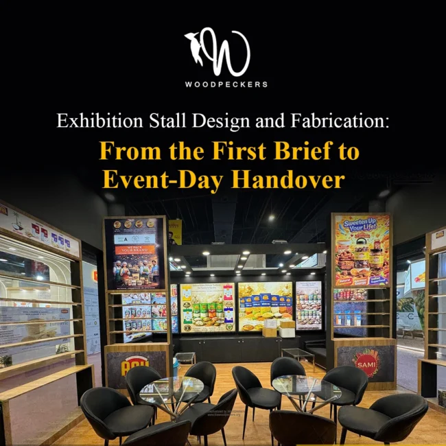 Exhibition Stall Design and Turnkey Fabrication – Event-Day Handover by Woodpeckers Fully fabricated exhibition stall designed by Woodpeckers ready for event handover, featuring product display racks, branded backlit posters, and client meeting tables.